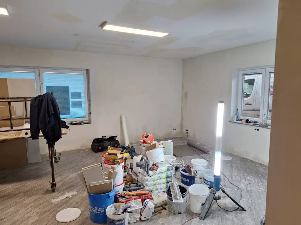Baustelle bei Teppich Schult mit Werkzeug, nackten Wänden, Staub, rollendem Gerüst und alten Leuchtstoffröhren