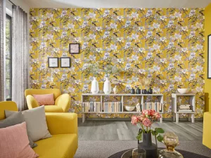 Sommerliche Wohnidee mit floralen Motiven, grauen und roséfarbenen Kissen, sonnengelber Tapete und weichmacherfreier Gardine