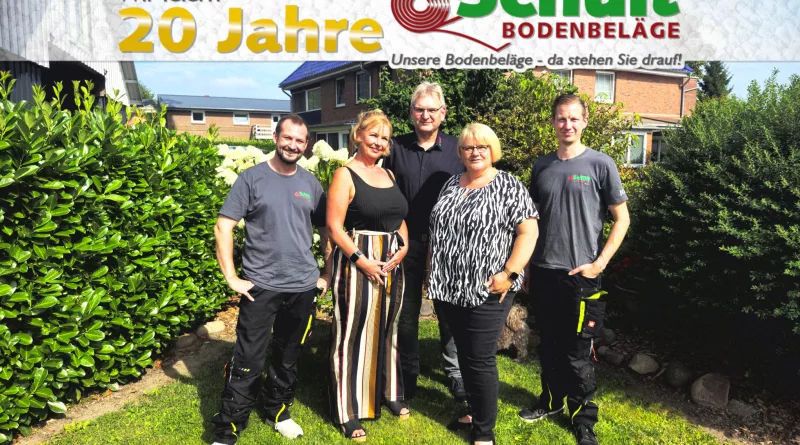 Das Team von Hartwig Schult Bodenbeläge im bunten Garten – Geschäftsführer Hartwig und Elsa Schult mit den Mitarbeitern Nico, Donny und Maureen. Oben im Bild Banderole mit „Wir feiern 20 Jahre“ und Firmenlogo.